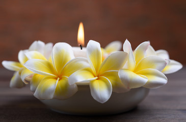 Beautiful Frangipani flowers in white bowl and candle light on wooden background,relaxation and meditation concept