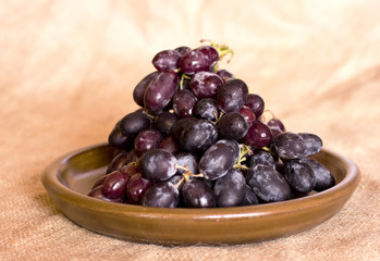 Blue grapes on a clay brown dish