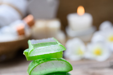 Alo Vera sliced,spa treatment and skincare products with flowers, soap,towel and herbal ball on rustic wood table,selective focus