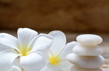 Pile of black zen stones and Frangipani flower on rustic wood background