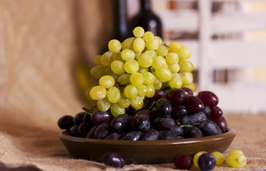 Blue and green grapes on a clay brown dish