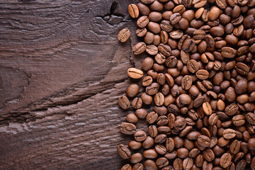 Brown coffee beans on an old wooden desk. Top view with a copy space for your text. Coffee background. Close up.