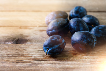 Blue organic plums on dark wooden background. Copyspace.
