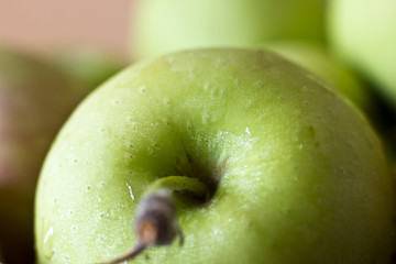 A green apple in drops of water. Macro shooting. Selective focus.