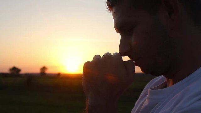 Silhouette of a man praying at sunset concept of religion. Silhouette man close up praying with sunset background.