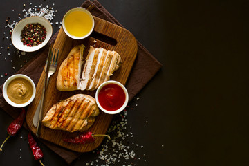 Grilled chicken breasts with spices on wooden desk. Top view. Space for copy. Toned image