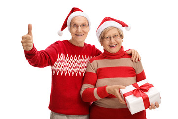 Obraz premium Elderly couple with present making thumb up sign