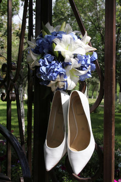 Wedding shoes and bouquet on a metal fence