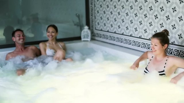Young happy people relaxing in hot tub in spa
