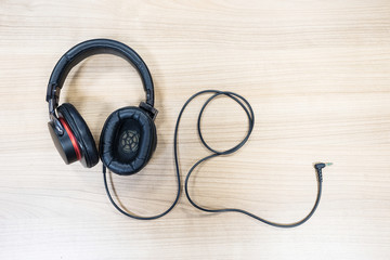 Full size headphone with cord on the wooden background