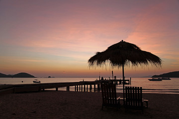 relax with beautiful sunset in the evening bridge chair beach bar beach umbrella boat silhouette at Koh Mak Trad Thailand