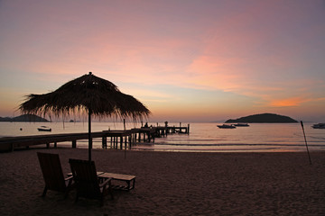 relax with beautiful sunset in the evening bridge chair beach bar beach umbrella boat silhouette at Koh Mak Trad Thailand