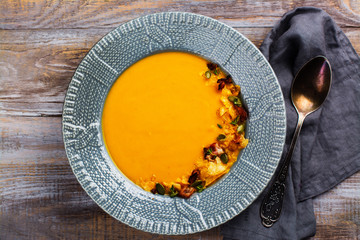 Vegetable pumpkin and carrot soup served with pumpkin seeds, potato chips and roasted bacon. Space for text