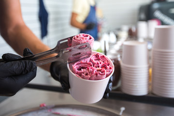 Stir-fried ice cream rolls at freeze pan. Rolled ice cream, hand made ice cream dessert. Fried ice cream machine with steel chilled pan.