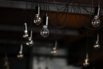 Retro Edison orange bulb design on Spider chandelier, easily hanging by black wires from ceiling.