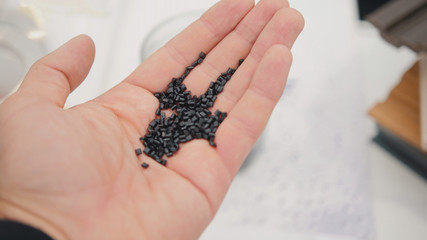 Plastic granules of polycarbonate in hand - extrusion manufactory