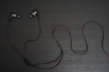 High quality Earphone with Black and Red wire on the black wooden table.