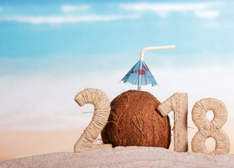 New Year inscription 2018, coconut with drinking straw and umbrella instead of the number 0 in sand on the beach.