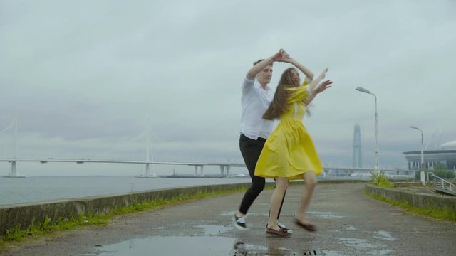 Happy boy and girl dance emotionally some joyful jive on a pier on a sea coast