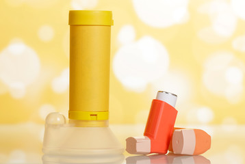 Inhalers and aerochamber on abstract yellow.