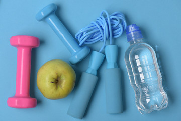 Jump rope, apple and barbells next to water bottle