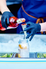 Bartender is pouring alcohol from a measuring glass into a glass over ice