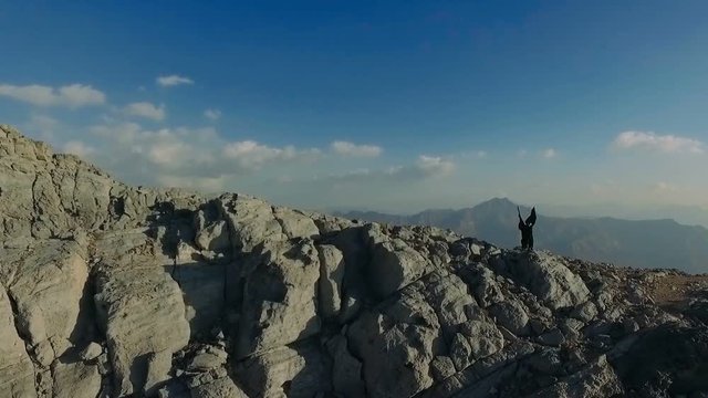 Dark witch young woman with isis wings is flying in the jebel jais mountains. Girl in zorro costume is practicing, exercising, waving cloak. Mystic lady dreams about freedom, game of thrones style