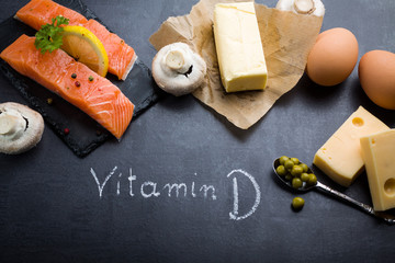 Black slate table with product rich in vitamin D and omega 3. Written word vitamin D by white chalk.