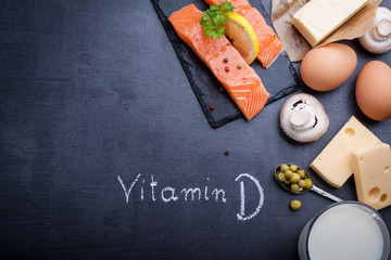 Black slate table with product rich in vitamin D and omega 3. Written word vitamin D by white chalk.