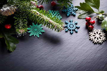Fototapeta na wymiar Background christmas decoration twig, red berries and wooden stars on back slate.