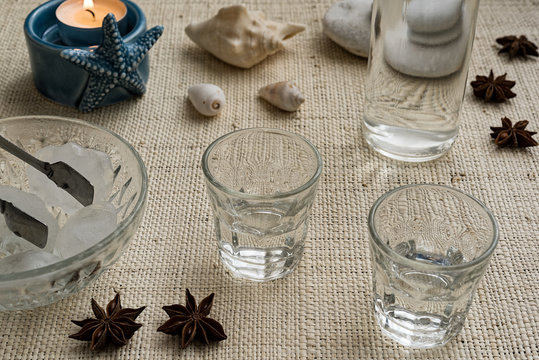 Glasses and bottle of traditional drink Ouzo or Raki on natural matting