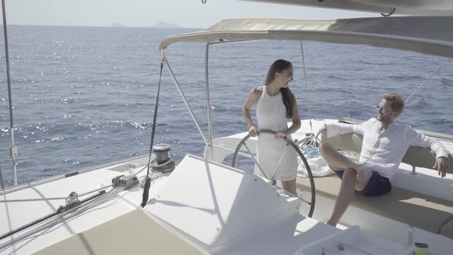 4k travel video rich young couple driving with their private yacht on sunny vacation day in meditteranian sea
