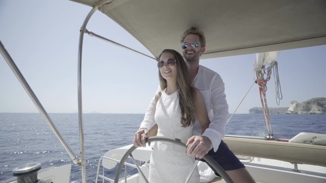 4k travel video happy honeymoon couple steering catamaran
