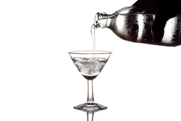 Pouring water or soda into a martini glass on white background