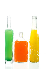 Three bottles with color drinks  stand on the reflecting surface.