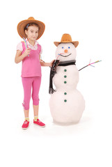 Cute girl holding a cola bottle near a snowman with scarf and hat