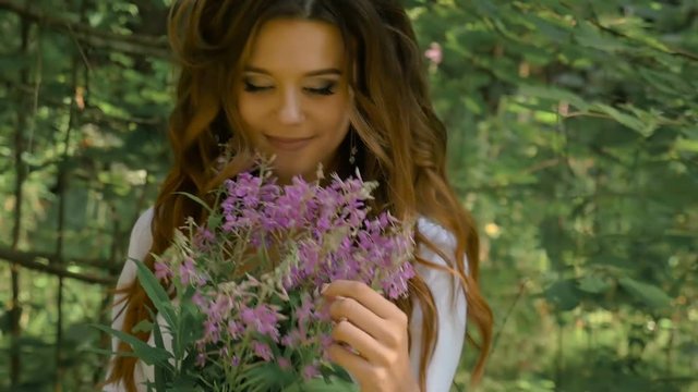 A beautiful sexy girl is holding a bouquet of wildflowers in her hands. It's a gift from her boyfriend.