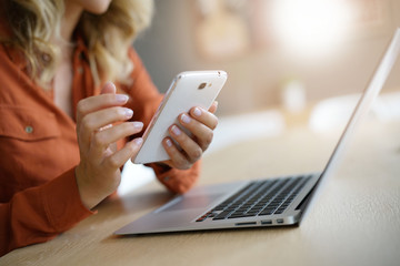Middle-aged woman at home connected on smartphone and laptop