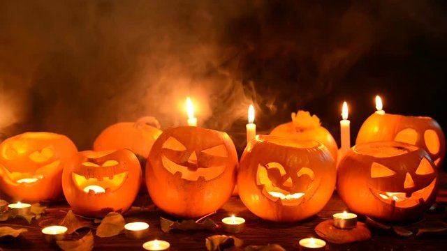 Halloween pumpkins with candles over dark background, closeup, front view, sliding video