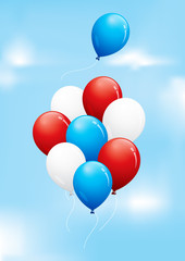 Red, white and blue balloons floating in a cloudy sky

