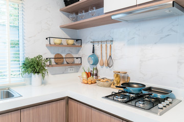 Kitchen wood utensils, chef accessories. Hanging copper kitchen with white tiles wall.