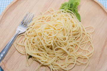 spaghetti without sauce with fork on wooden plate