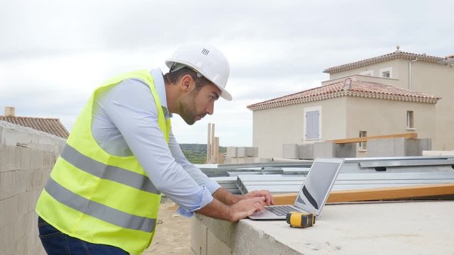 handsome young man foreman architect supervising a new house construction site