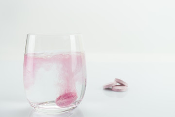 Glass of water with just disintegrating pink tablet