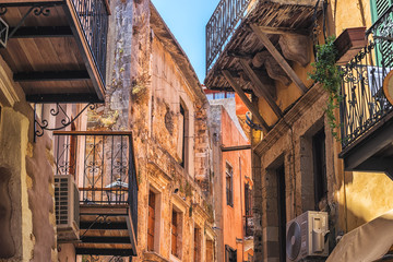 Old narrow street with stone walls and wooden windows in Chania city, Greece.