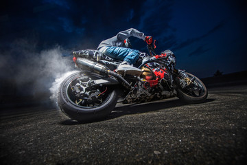 Fototapeta na wymiar Moto rider making a stunt on his motorbike. Biker doing a difficult and dangerous stunt.