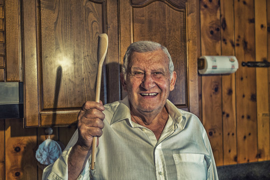 elderly man holding wooden cooking spoo