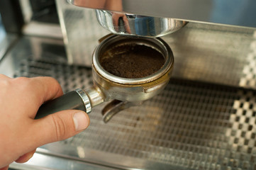 Barista prepares espresso, holding a holder of a coffee machine