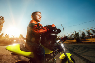 Child on his small motorcycle. Small biker dressed in a protective suit and helmet.