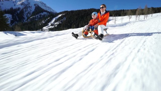 mother and son having fun sledging on snow
